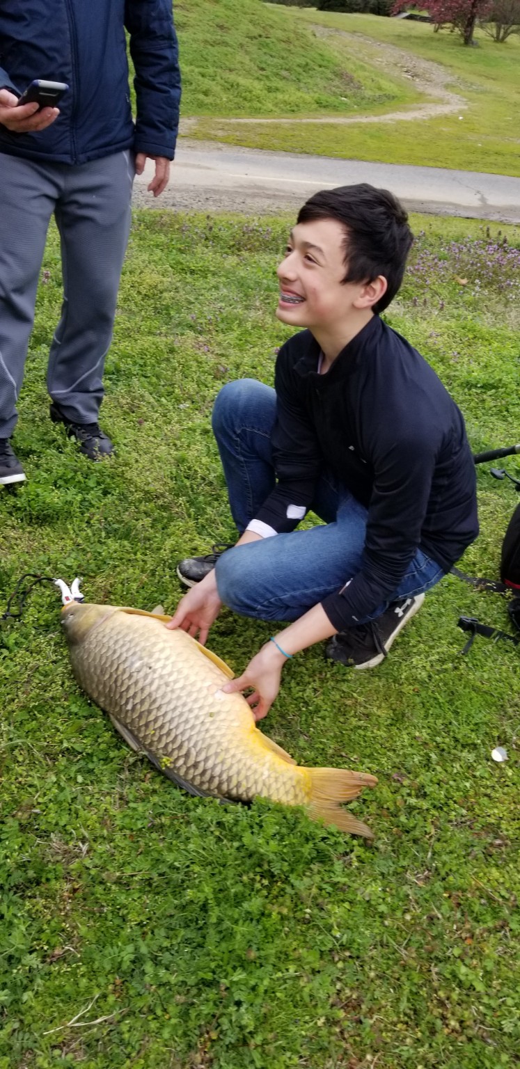 A young angler smiling beside a large catch
